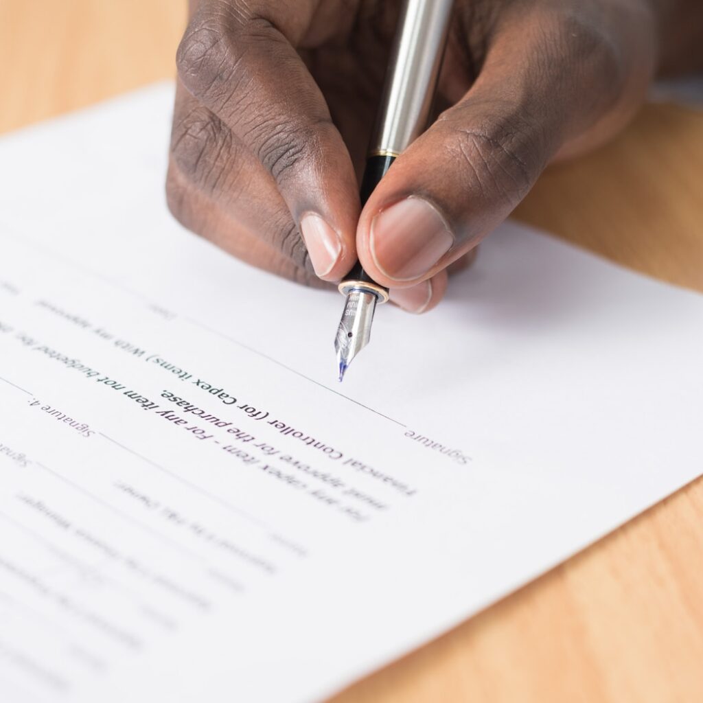 Photograph of a man signing a document.