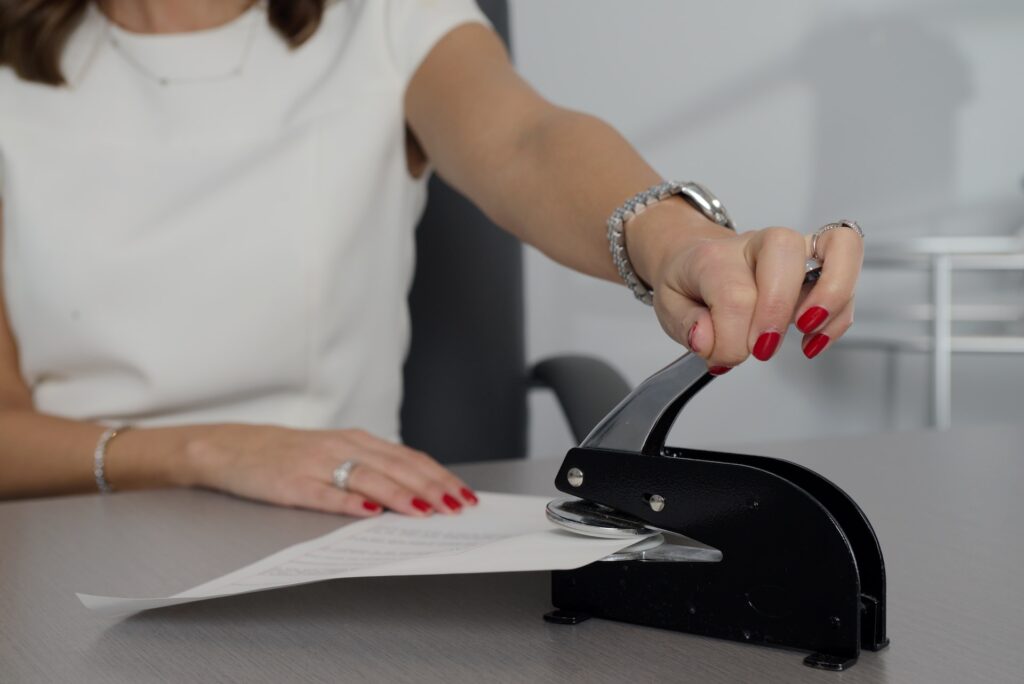 Photograph of a woman stapling a document.