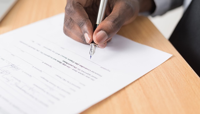 Photo of a man signing a document.